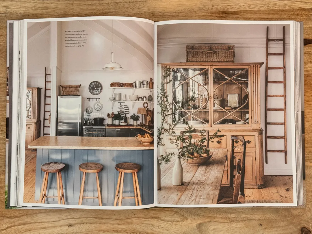 White kitchen with a blue island and wooden stools beside a rustic dresser