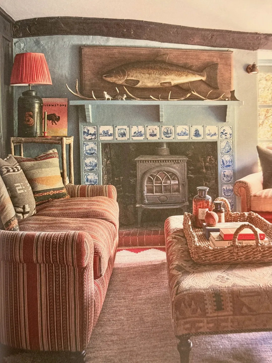 Cosy cottage sitting room with a striped sofa, wood stove and blue-and-white tiles, from COCOON by Ali Heath