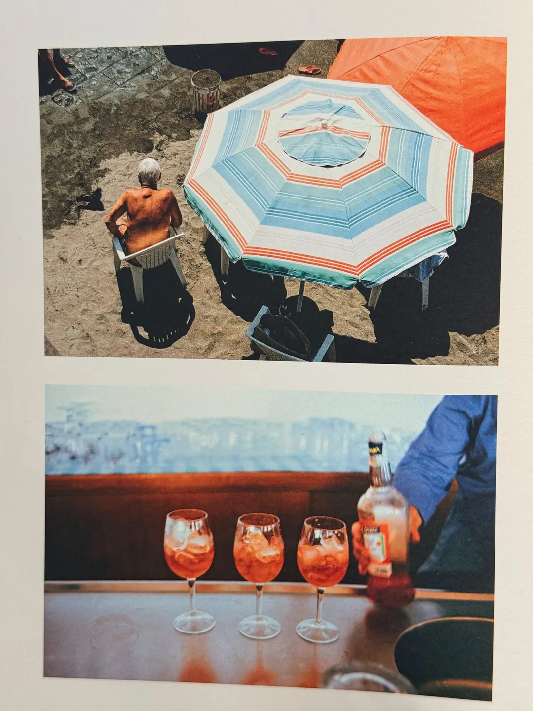 Striped beach umbrella above, and three spritz glasses on a bar by the sea