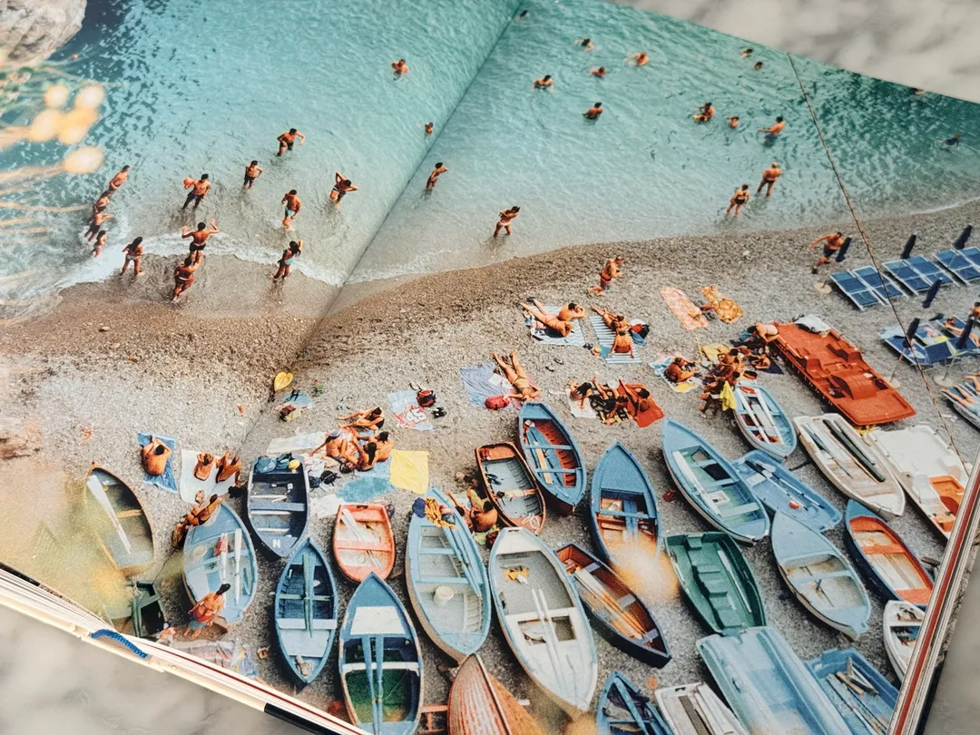 Aerial view of colourful rowboats and sunbathers on a crowded beach