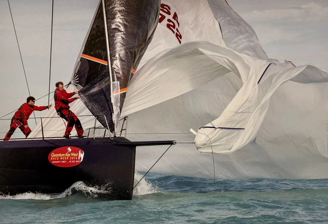 Racing crew in red gripping the rail as a spinnaker billows, from Sailing America by Onne van der Wal