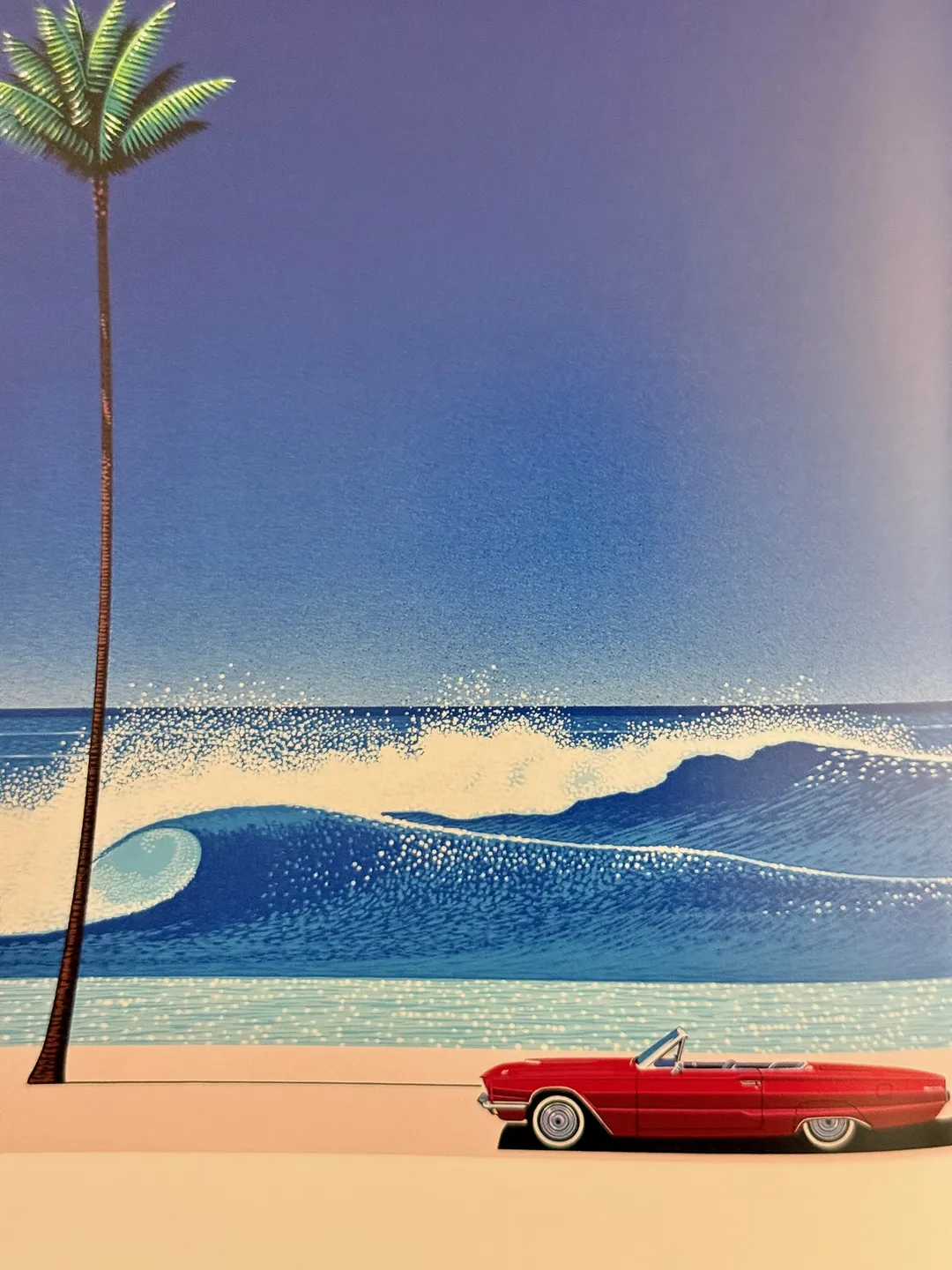 Red convertible beneath a tall palm and a curling wave