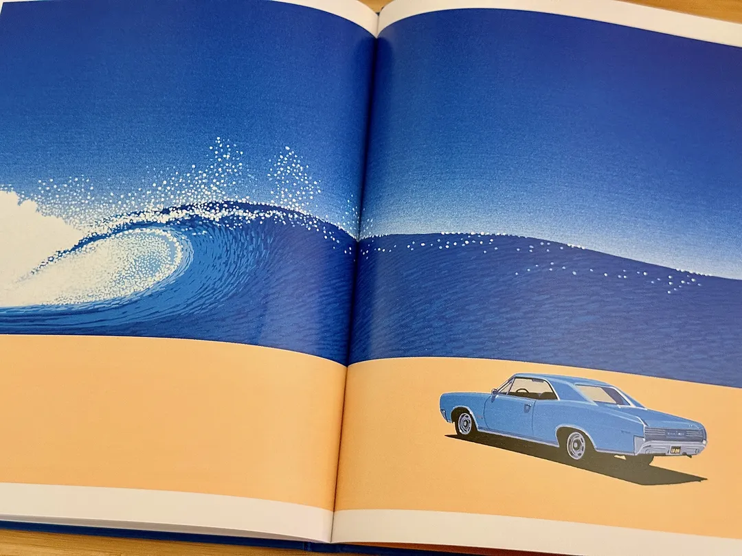 Blue muscle car on a beach beside a breaking wave
