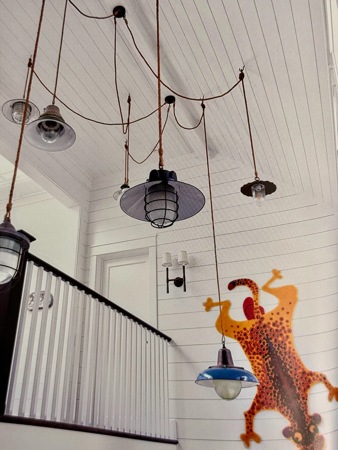 White staircase hung with industrial pendant lights and a leopard wall hanging