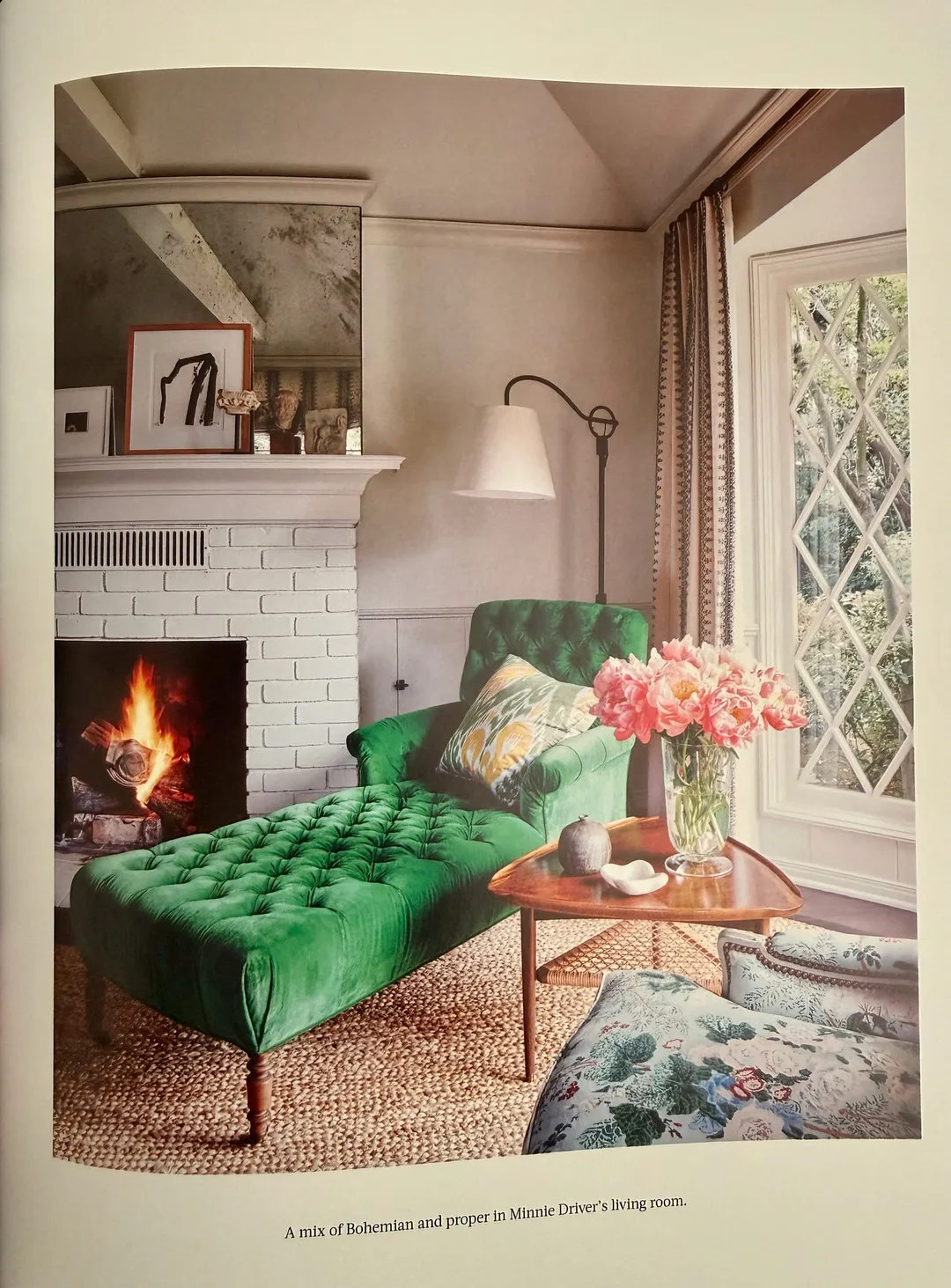 Green velvet chaise beside a white brick fireplace