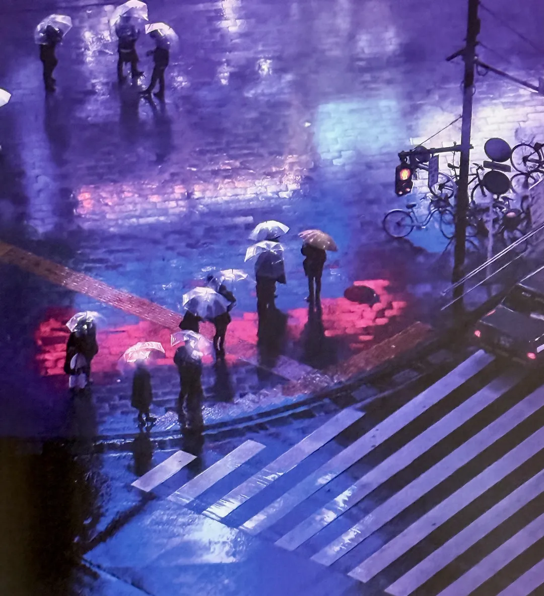 Pedestrians with umbrellas crossing a rain-soaked crosswalk at night