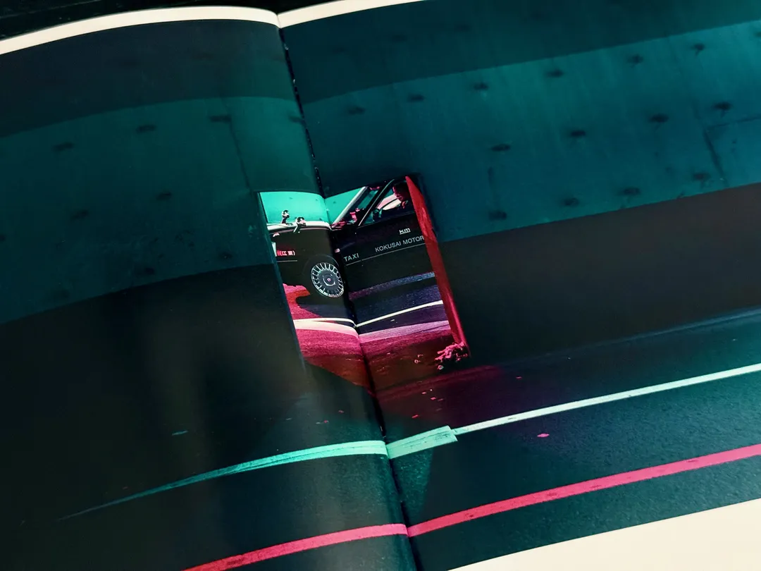 Red taxi seen from above on a teal road at night