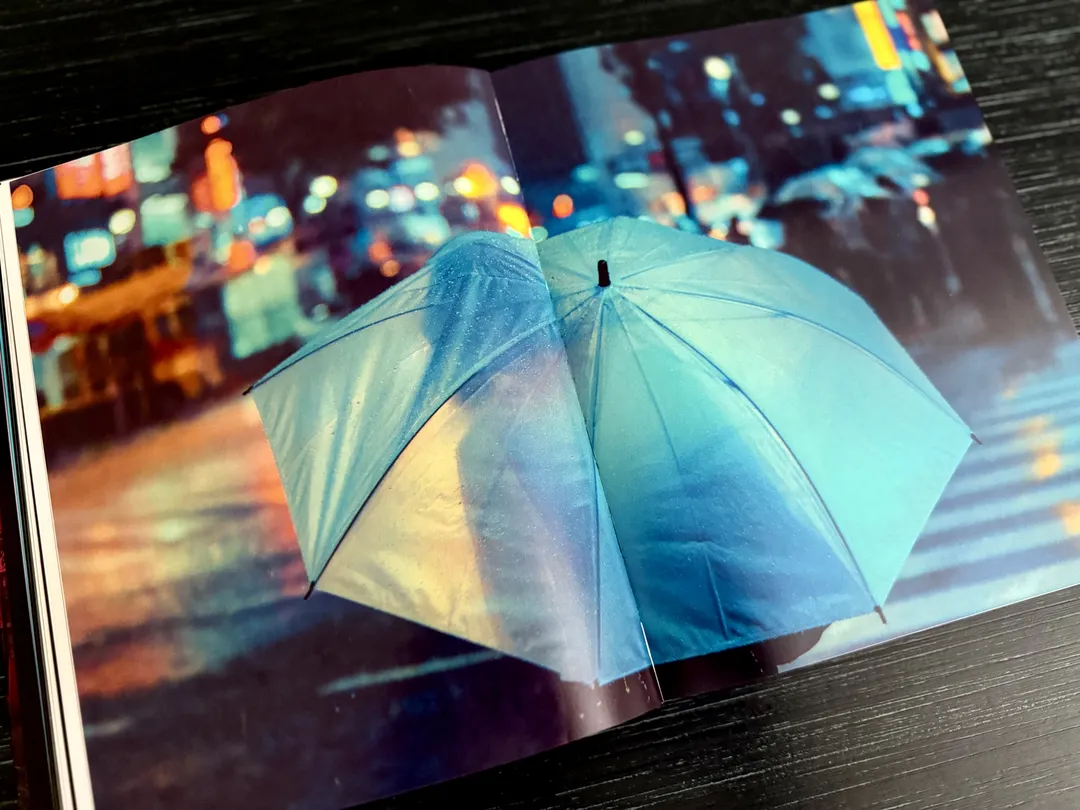 Clear umbrella glowing turquoise in the rain