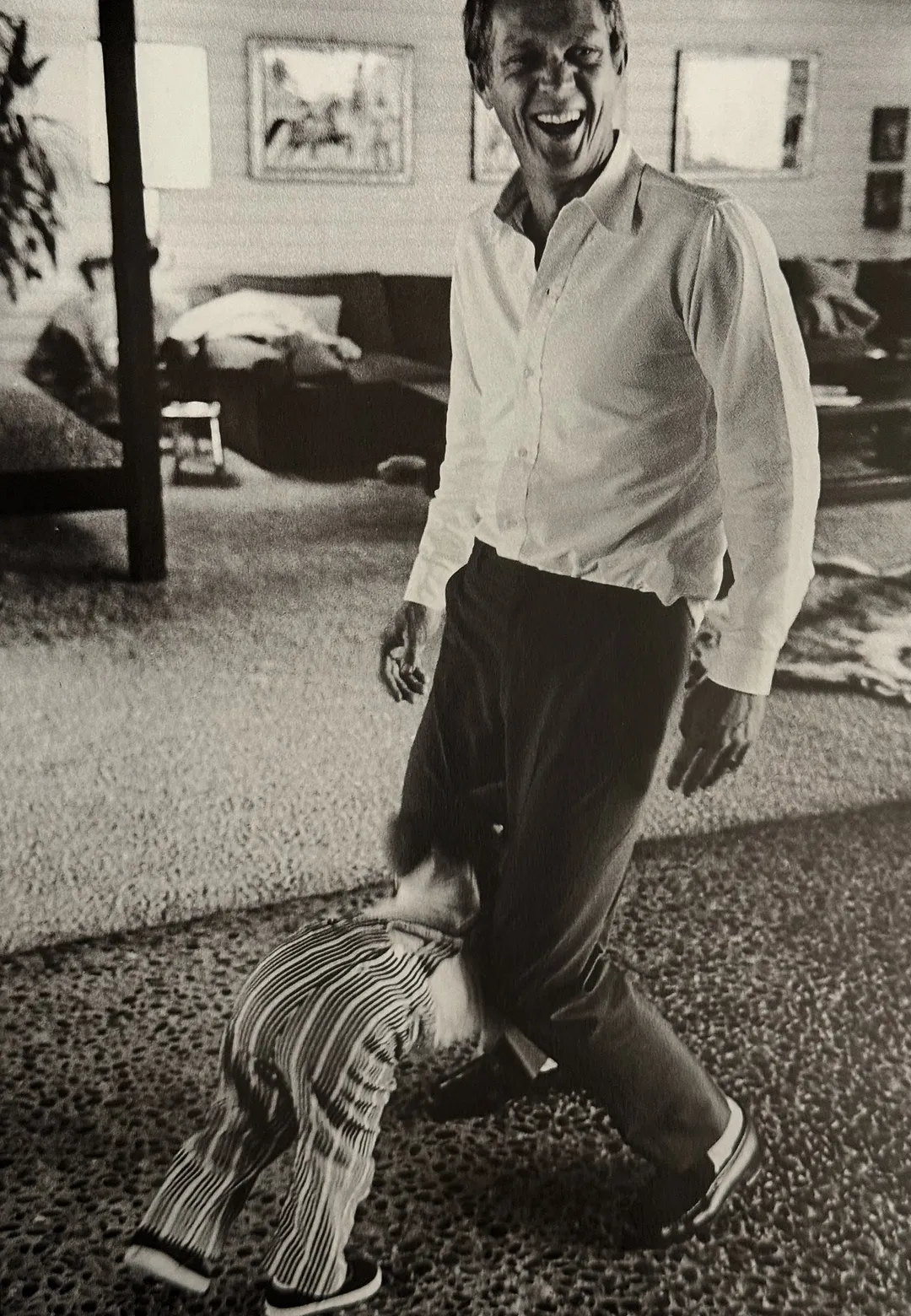 McQueen laughing as a small child hugs his leg